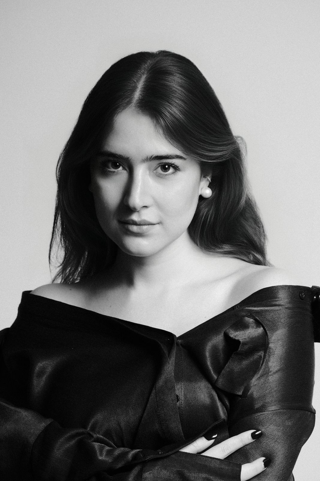 Paola Beatriz Miralles, black and white portrait, hair down, arms crossed in a black satin top