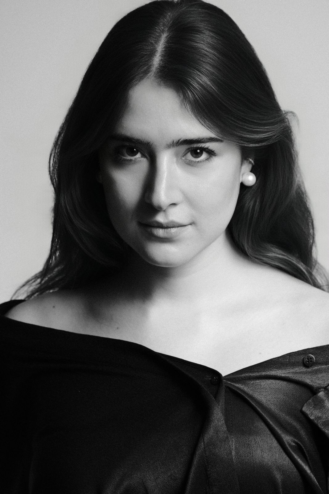 Paola Beatriz Miralles, black and white close-up, hair down, off-the-shoulder black top, direct gaze